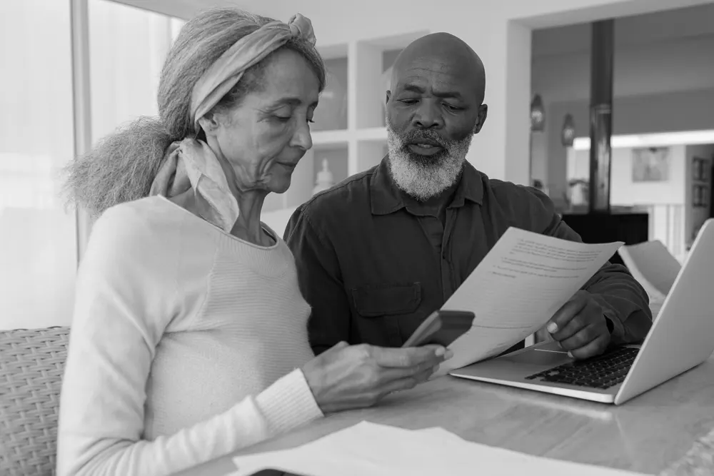 A couple sits at their kitchen table reviewing resources on what they should expect at an Alzheimer's screening appointment
